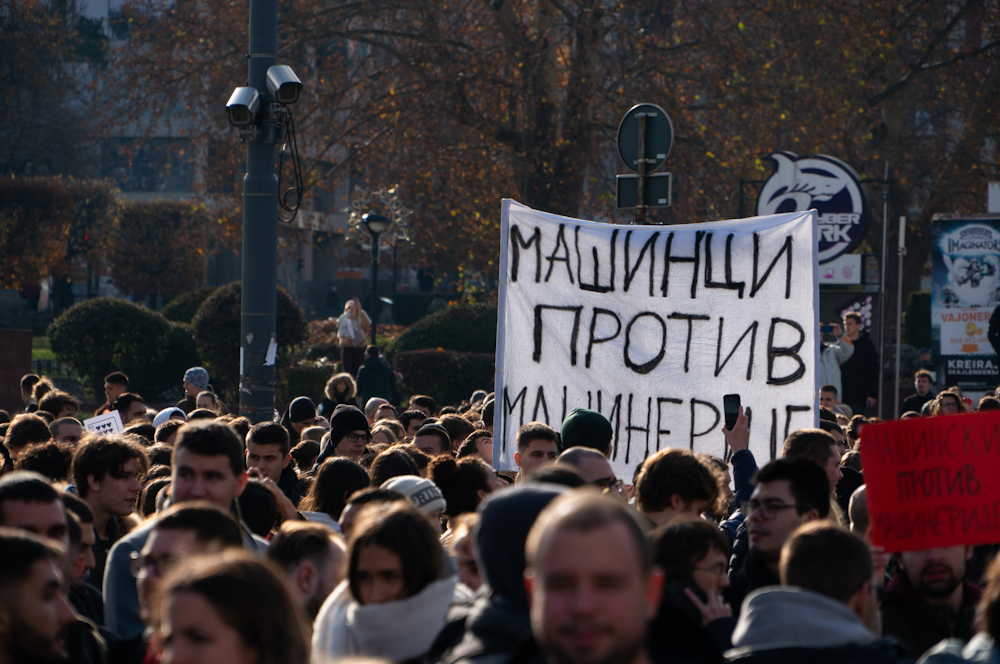 Student protest crowd holding a banner reading 'Mašinci protiv mašinerije'